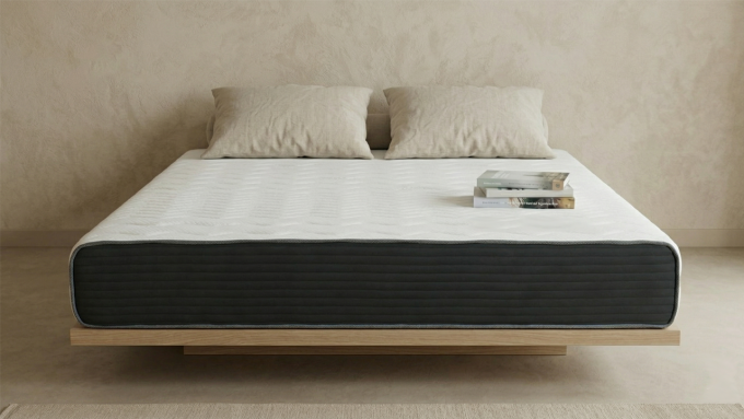 床墊主體:畫面中央是一張放置在淺色木質懸浮床架上的「奶凍捲床墊」。床墊表面為純白色波浪紋路織物,側邊由深灰色水平條紋布料包覆,營造出層次分明的現代簡約感。