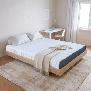 這張圖片展示了一間明亮簡約的臥室。主題是放在淺色木質懸浮床架上的「奶凍捲床墊」。床墊表面呈現白色波浪紋路,側邊則是深灰色的布料。 床墊上鋪著兩顆白色枕頭,床尾則擺放著一條米色的人字紋羊毛毯,毯子末端有流蘇設計。 臥室牆面為米白色,掛著一幅簡約的藝術畫作。背景處有一張白色的書桌,上面擺放著筆記本和一盞檯燈,旁邊則是一張白色單椅。 木地板上鋪著一張大尺寸的米色長毛絨地毯。右側有一扇落地窗,透進自然光線,窗邊掛著輕透的白色紗簾。整個空間呈現舒適、清新的氛圍。