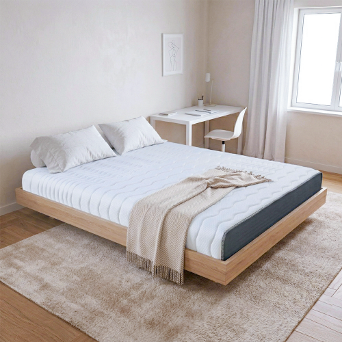 這張圖片展示了一間明亮簡約的臥室。主題是放在淺色木質懸浮床架上的「奶凍捲床墊」。床墊表面呈現白色波浪紋路,側邊則是深灰色的布料。 床墊上鋪著兩顆白色枕頭,床尾則擺放著一條米色的人字紋羊毛毯,毯子末端有流蘇設計。 臥室牆面為米白色,掛著一幅簡約的藝術畫作。背景處有一張白色的書桌,上面擺放著筆記本和一盞檯燈,旁邊則是一張白色單椅。 木地板上鋪著一張大尺寸的米色長毛絨地毯。右側有一扇落地窗,透進自然光線,窗邊掛著輕透的白色紗簾。整個空間呈現舒適、清新的氛圍。